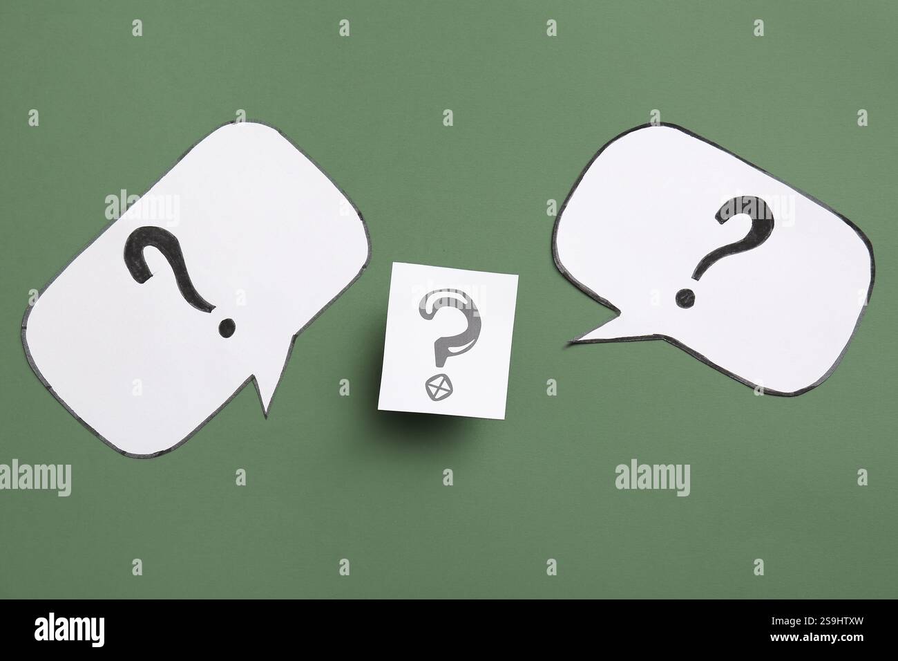 Speech bubbles with question marks on green background Stock Photo