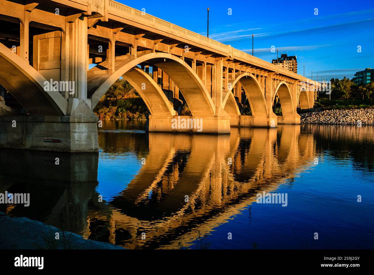 A bridge spans a river with a reflection of the bridge in the water ...