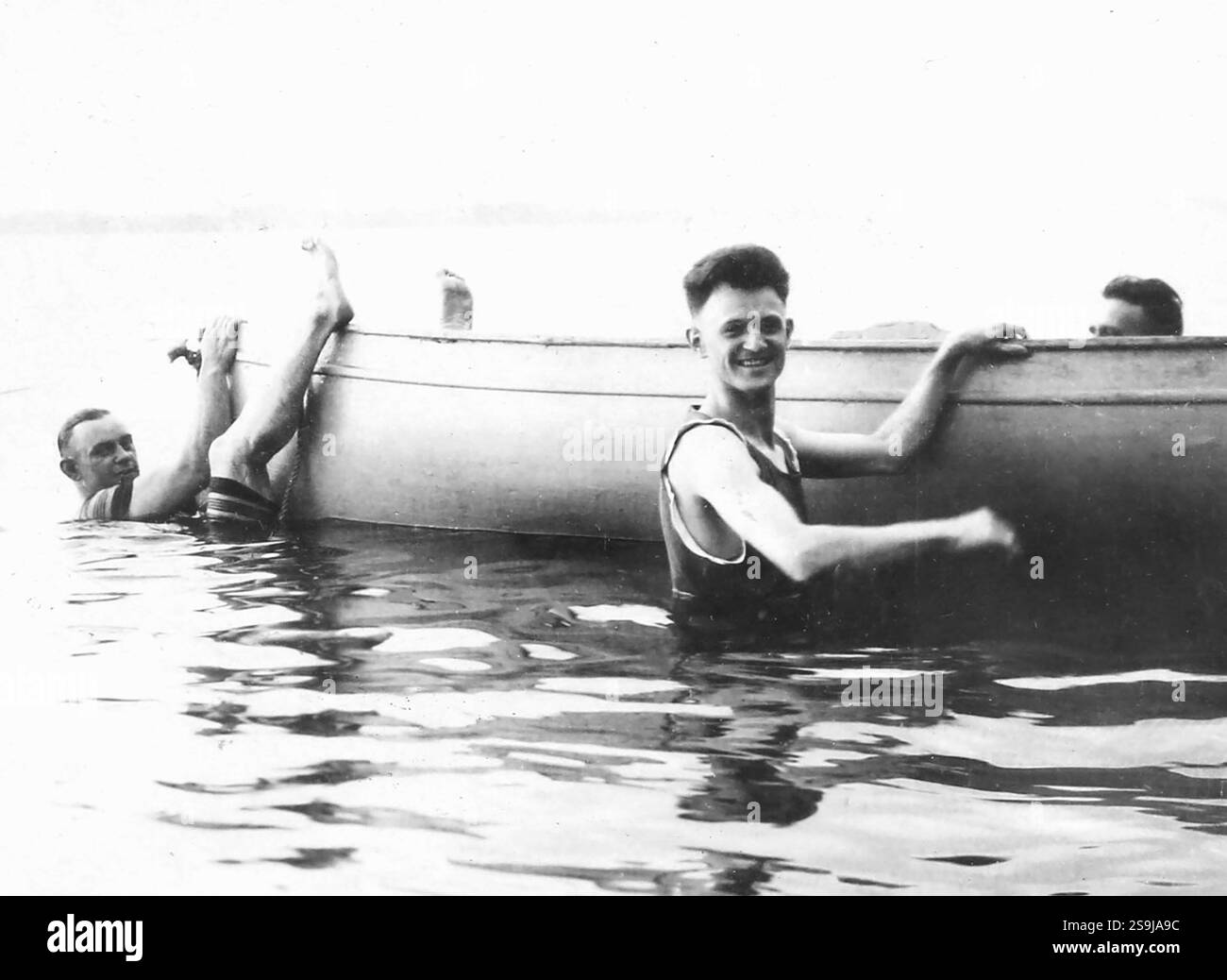 Three men clown around on the outside of boat, circa 1910. Stock Photo