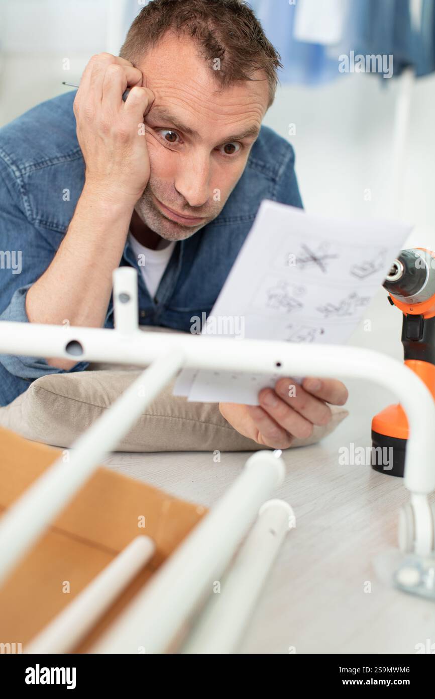 frustrated man trying to understand furniture assembly Stock Photo - Alamy