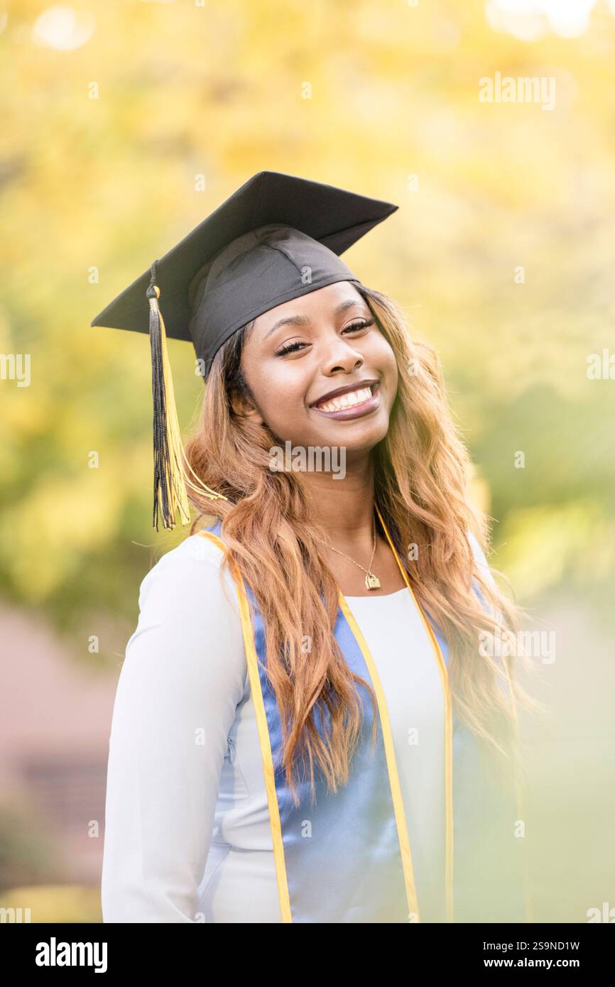 Black woman in graduation cap with fall leaes in background Stock Photo ...