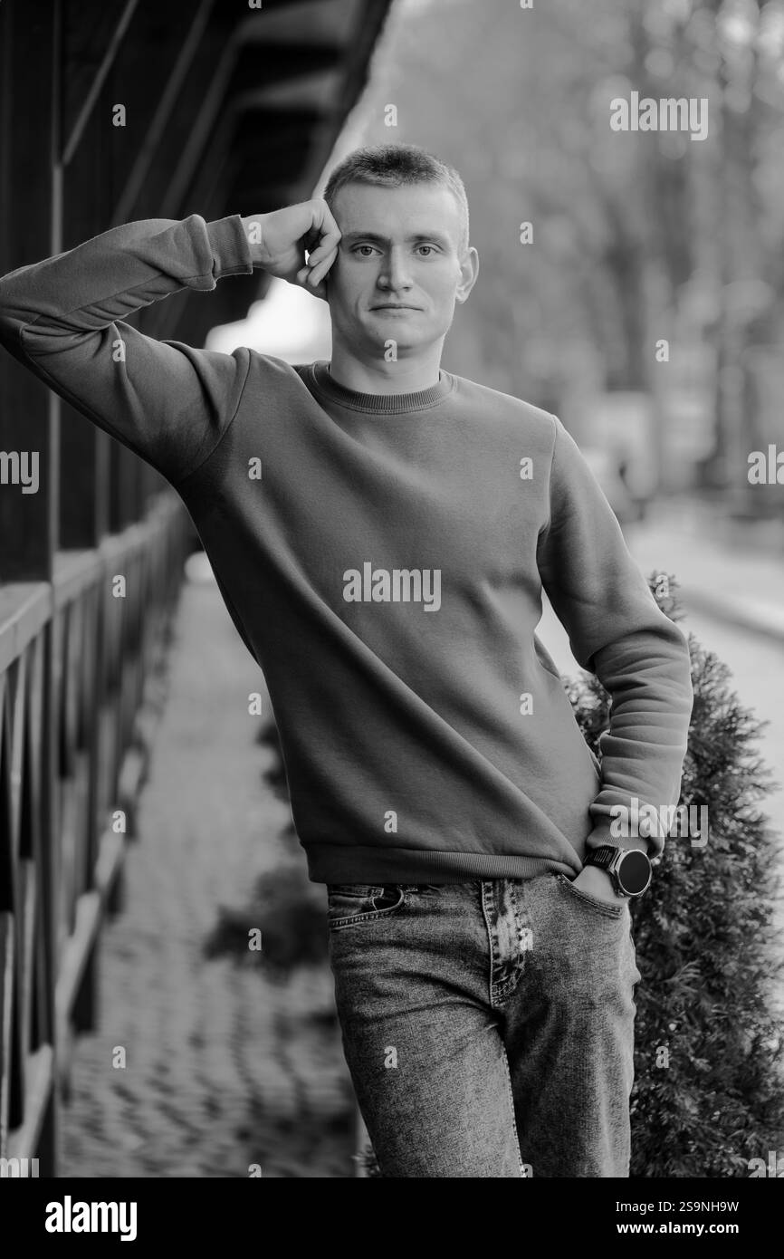 Casual Black and White Portrait of a Young Man Leaning Against a Wall ...