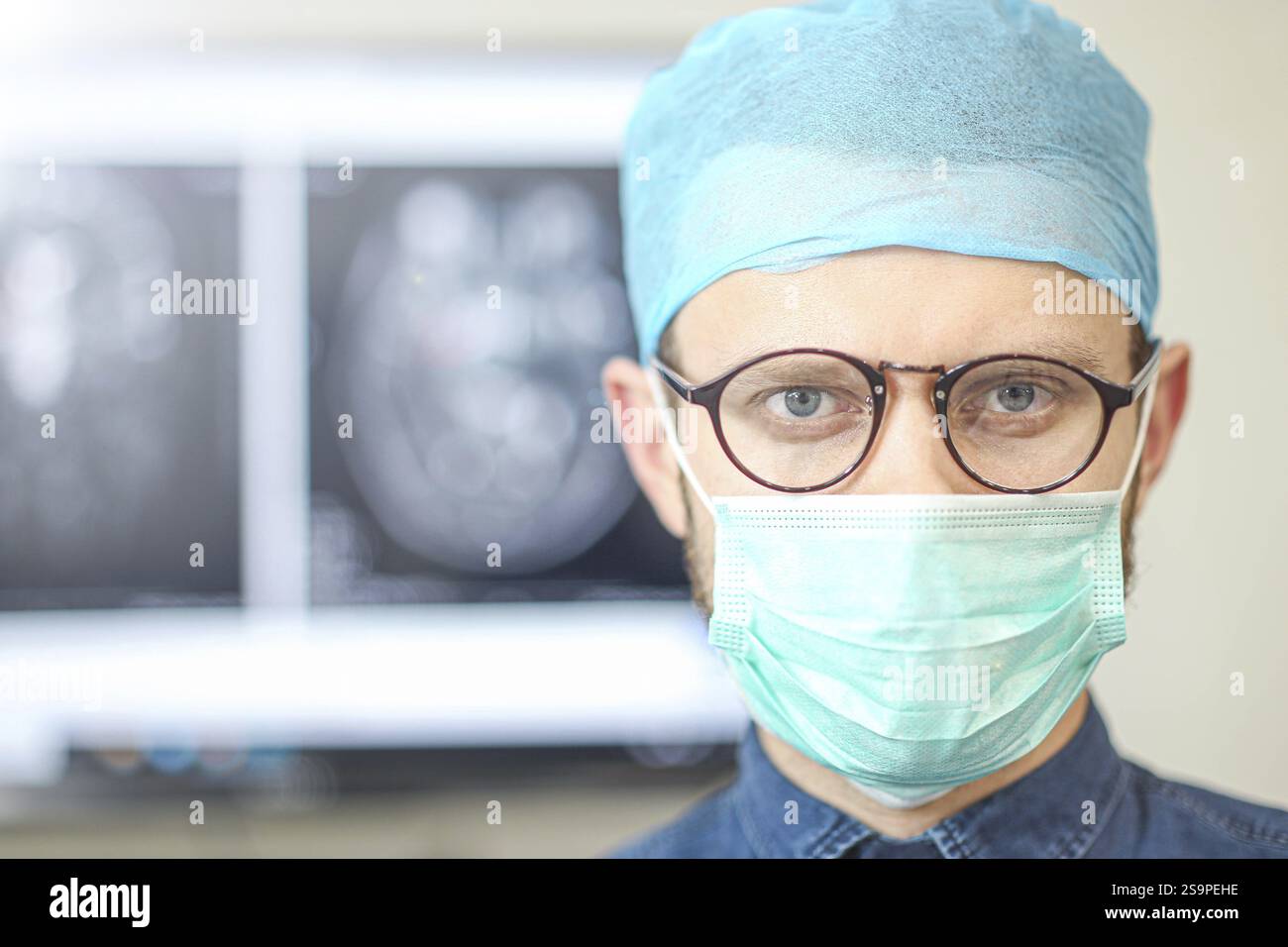 A surgeon with an alert expression, standing before medical screens Stock Photo