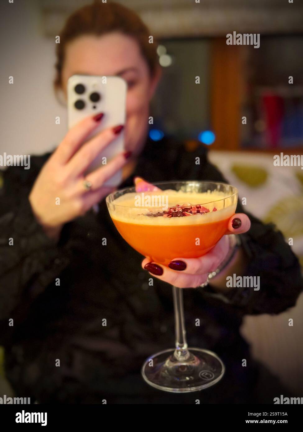 A woman photographing her cocktail to put it on social media - Smartphone Captured Stock Image