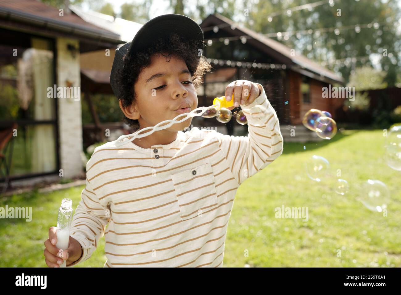 Blowing Soap Bubbles Outdoors in Sunlit Backyard Stock Photo