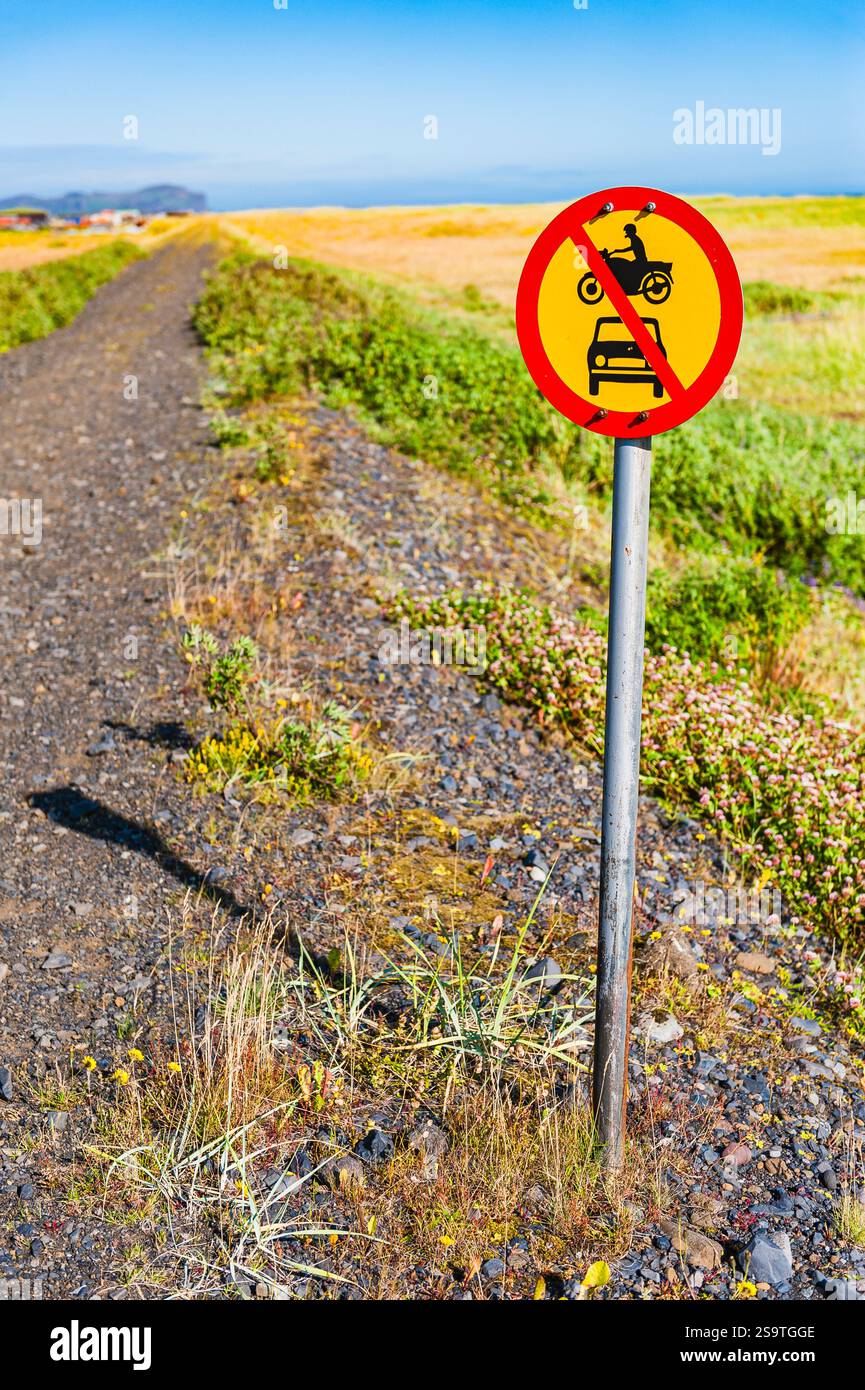 A bright red sign stands beside a gravel path in Iceland, clearly ...