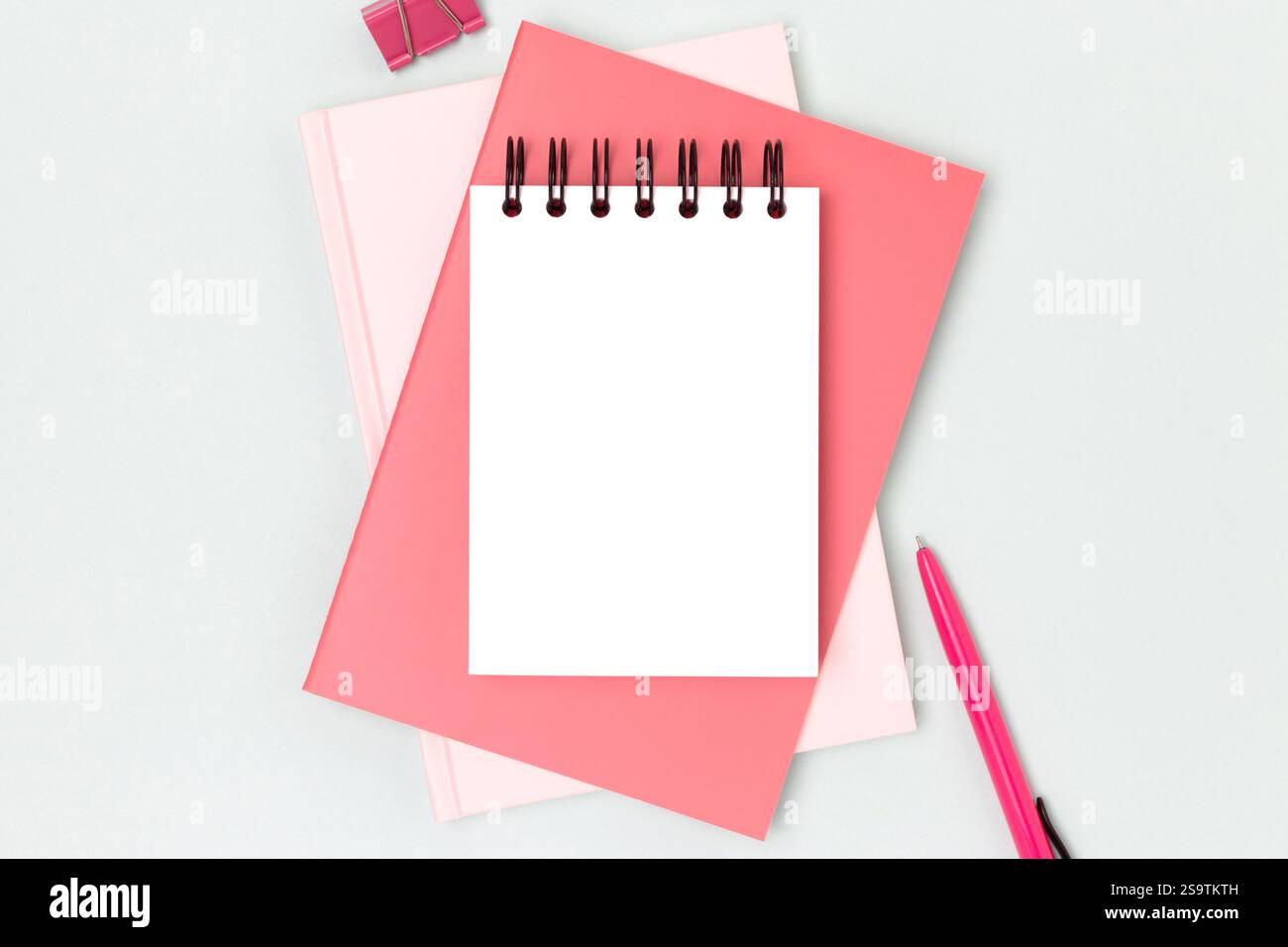 Workspace with clean notepad mock up and pink colored stationery on a blue background. Business concept with copy space. Stock Photo