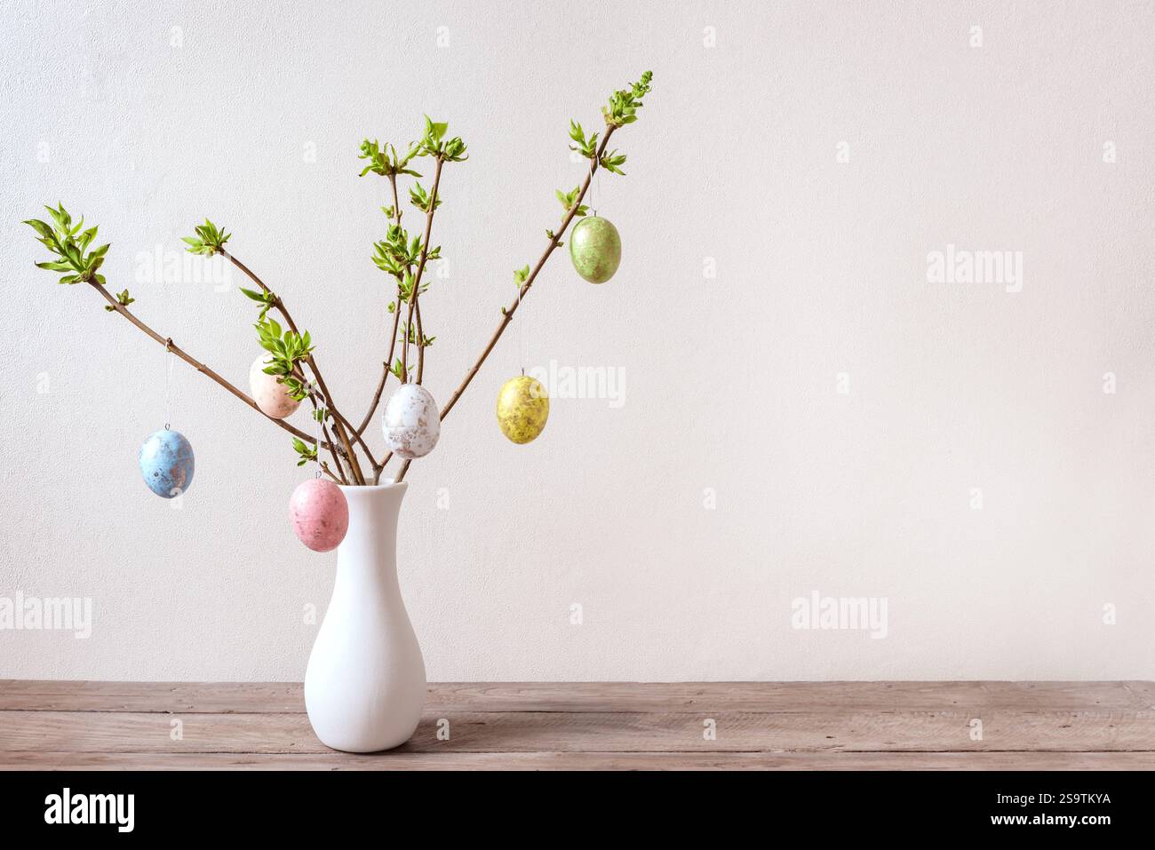 Painted Easter eggs on spring twigs, neutral background, minimal composition. Happy Easter bouquet. Stock Photo