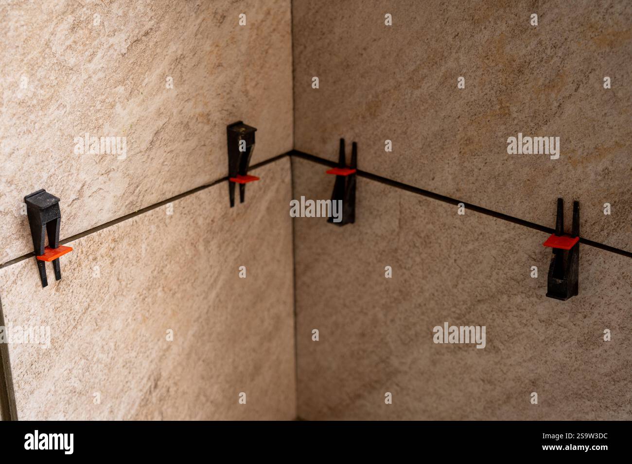 Tile leveling system with plastic clips and wedges, shot while the tile mortar sets. Wall tiling. Stock Photo