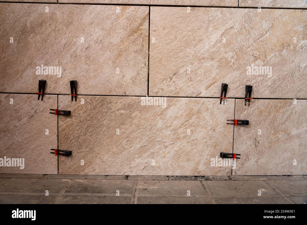 Tile leveling system with plastic clips and wedges, shot while the tile mortar sets. Wall tiling. Stock Photo