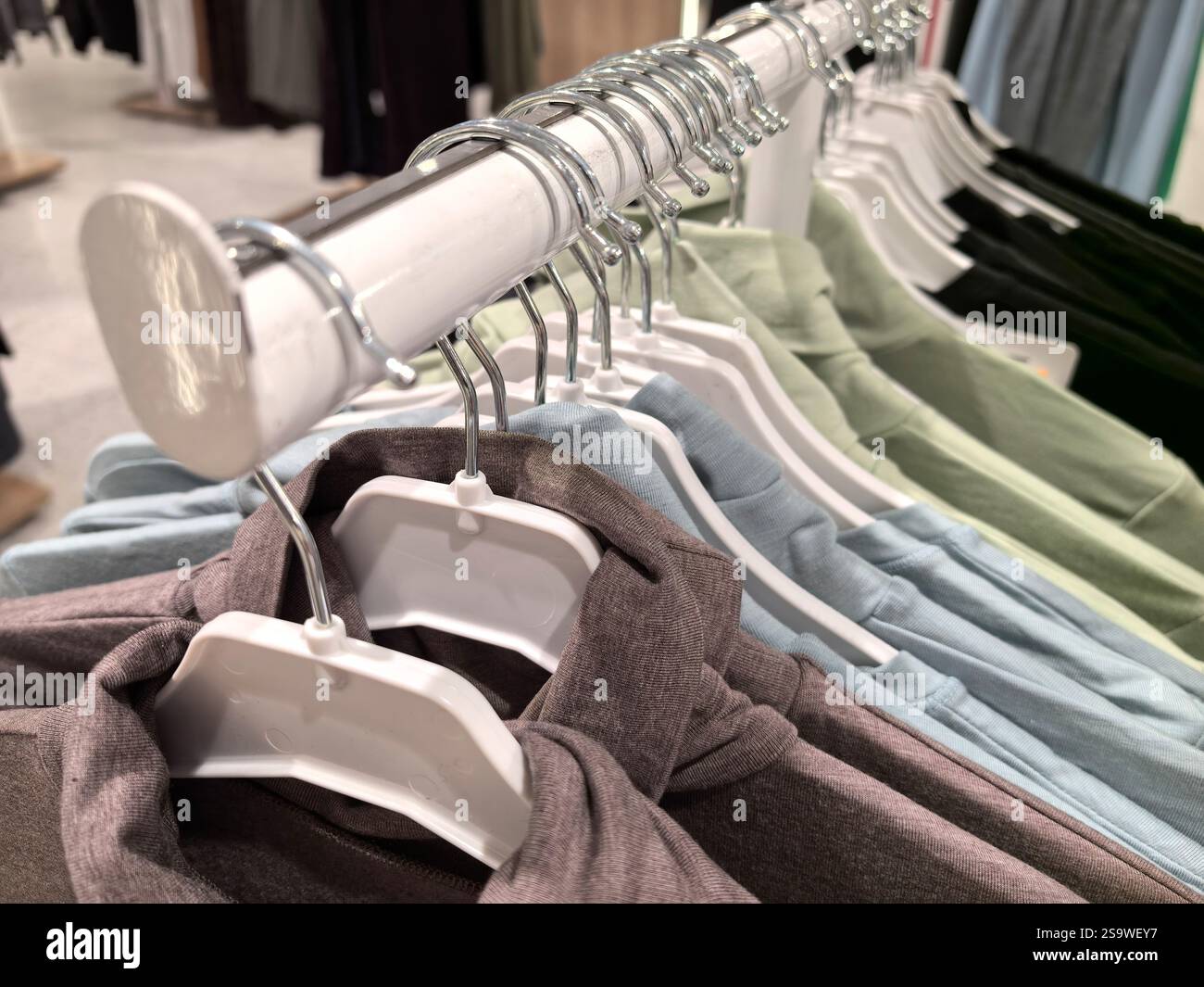 A row of vibrant clothing items is displayed on hangers in a contemporary retail environment. Soft pastel colors and textures invite shoppers to explo Stock Photo