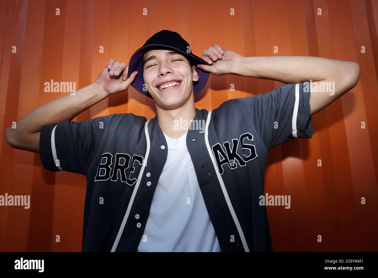 Smiling Young Man Holding His Hat and Laughing Stock Photo