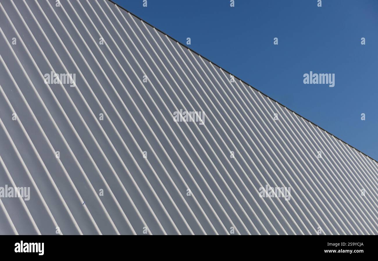 ribbed metal roofing in silvery gray tones. architectural patterns against clear sky Stock Photo