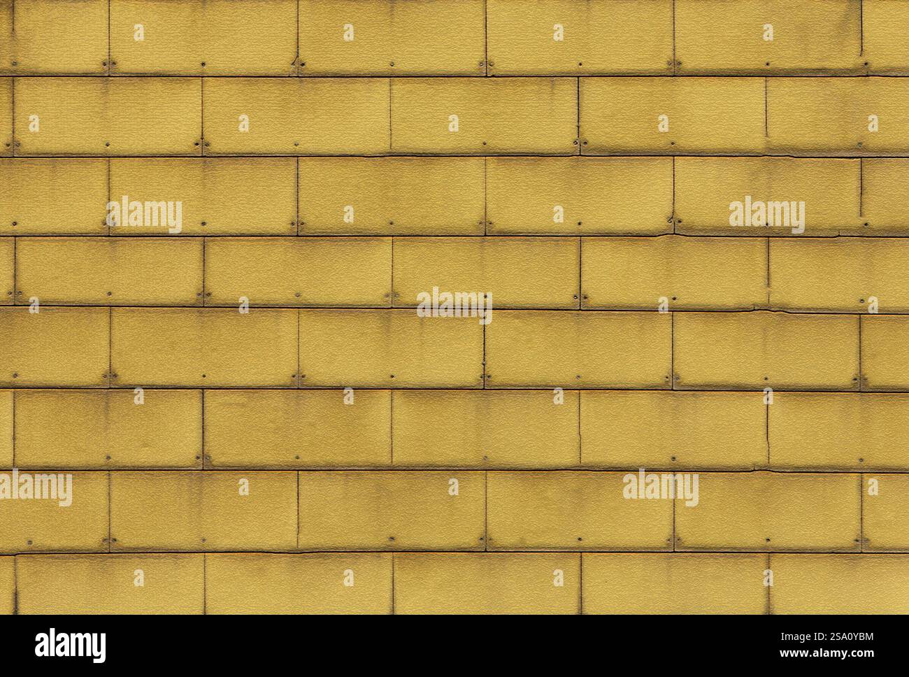 Yellow wall tiles creating repeating pattern with rivets Stock Photo
