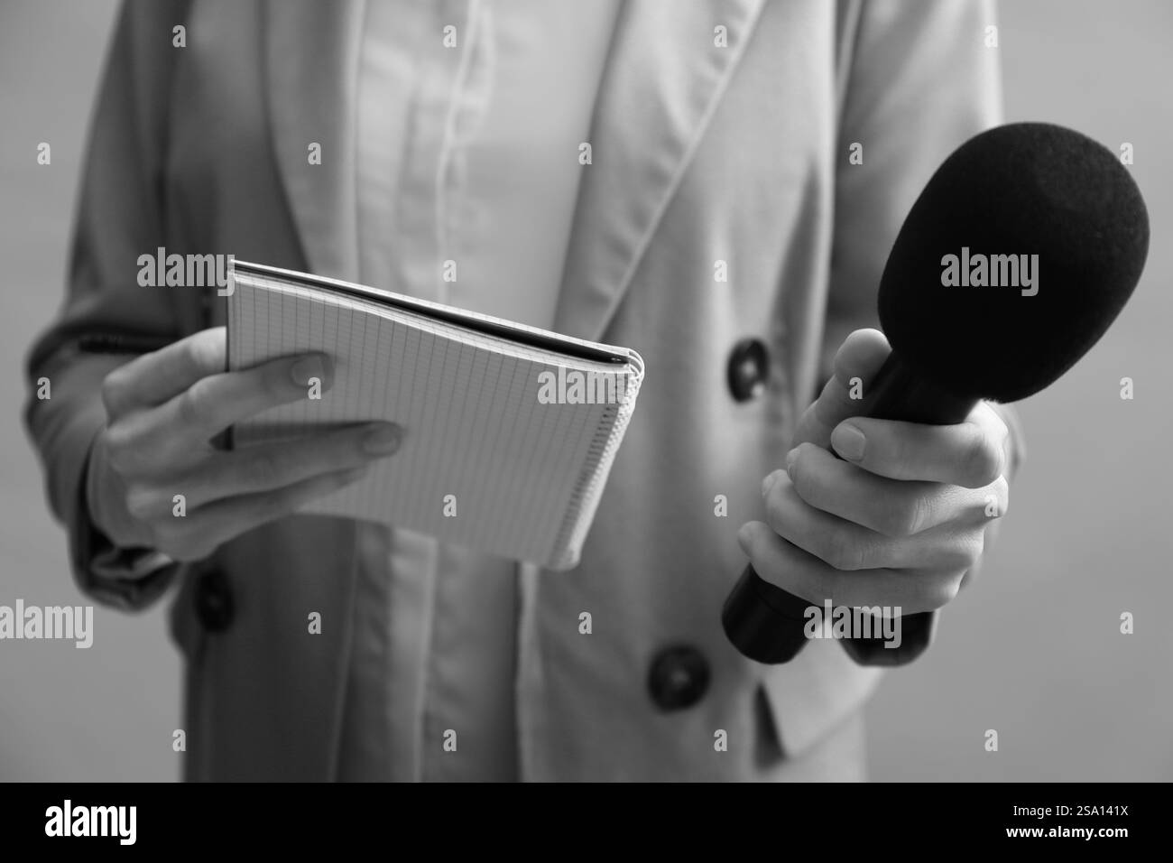 Journalist with microphone and notebook, closeup. Toned in black-and ...