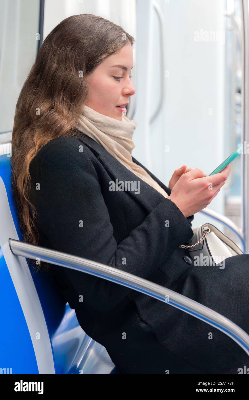Side view happy Young Woman Laughing While Using Smartphone on Subway Train Stock Photo