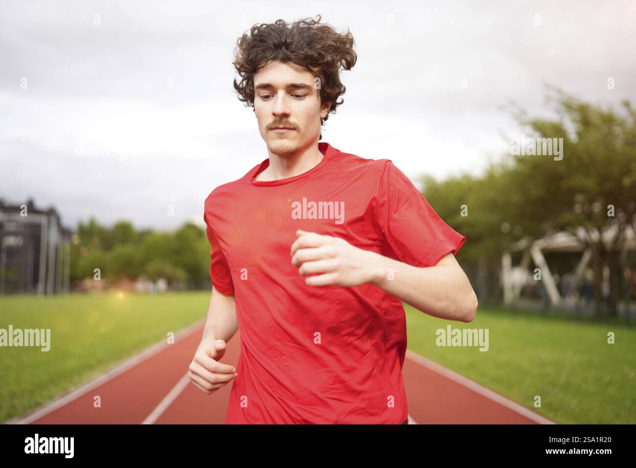 Close-up motion photo of a caucasian young man running along a track ...