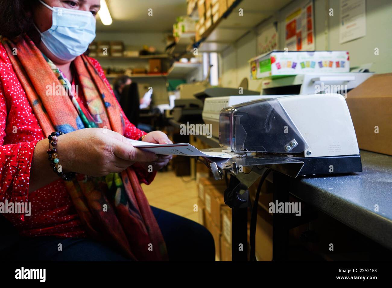 Disabled worker working in the printing, reprography and marking workshop. Binding with electric stapler. work with disabilities 016794_024 Stock Photo