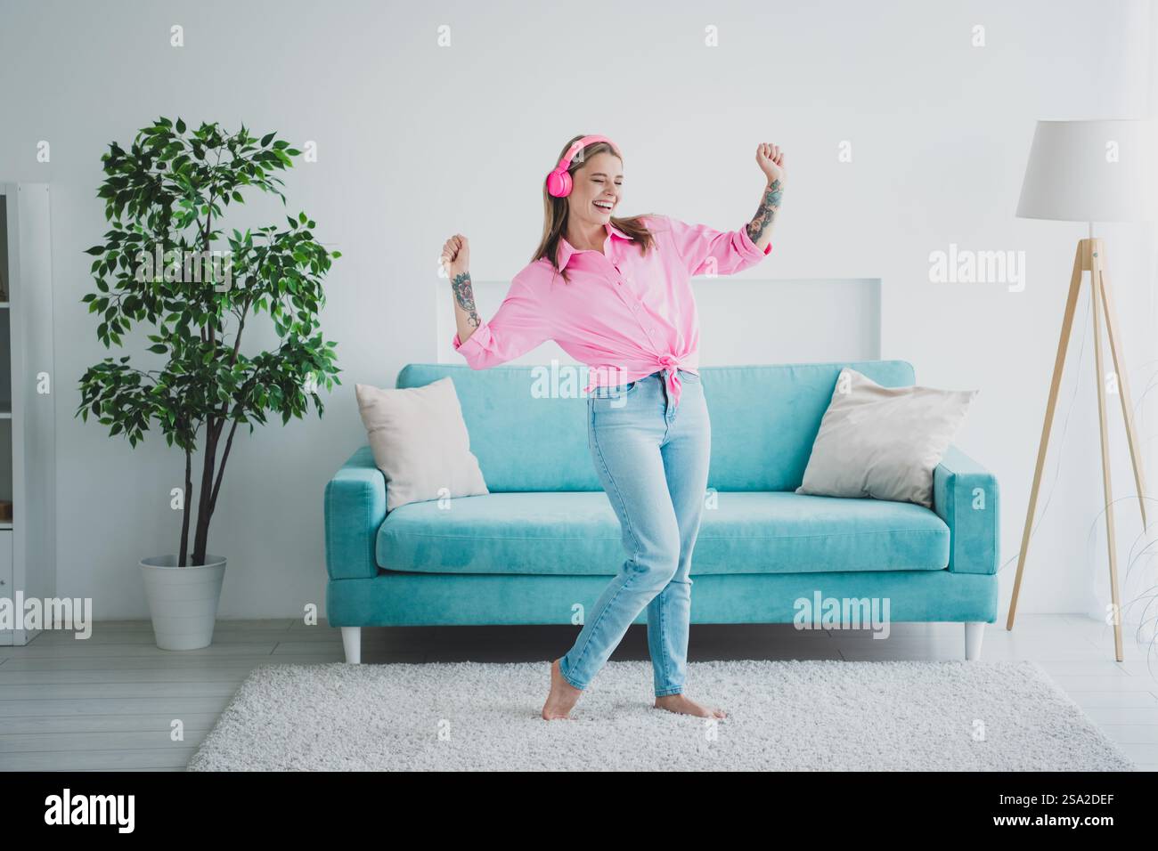 Joyful young woman enjoying music and dancing in bright, cozy living ...