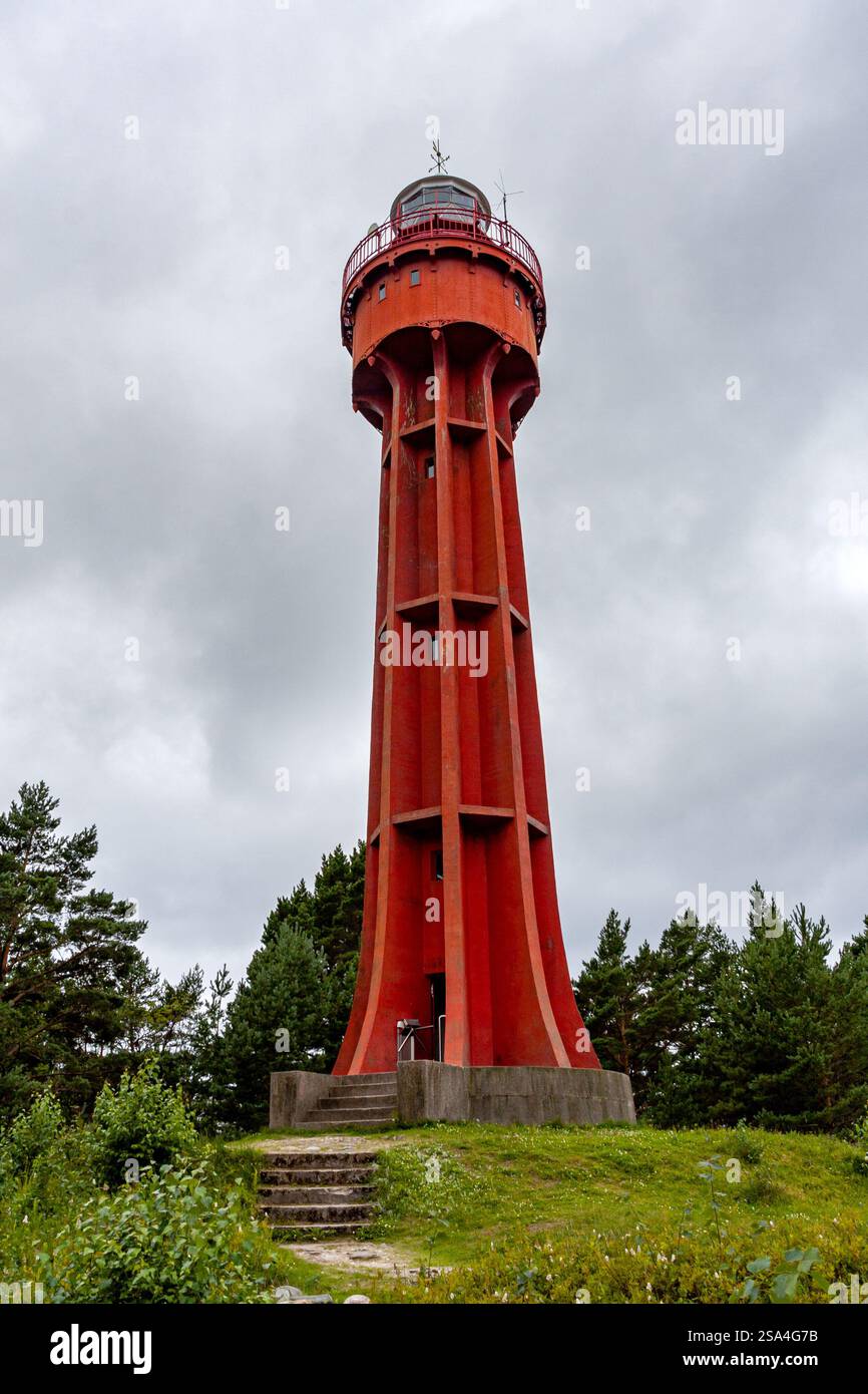 A full shot of a tall, red lighthouse tower on a cloudy day, featuring a unique, segmented structure and a set of stone steps at its base. The tower i Stock Photo