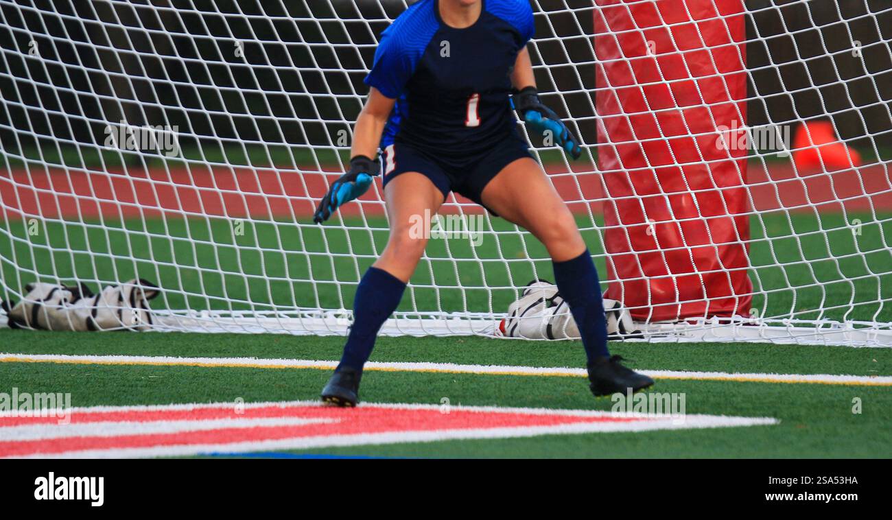 A Focused Goalkeeper Positions Herself In Front Of The Net Ready For 