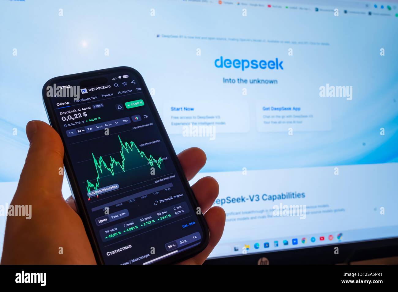 Analyzing stock trends on a smartphone while using a computer for insights Stock Photo