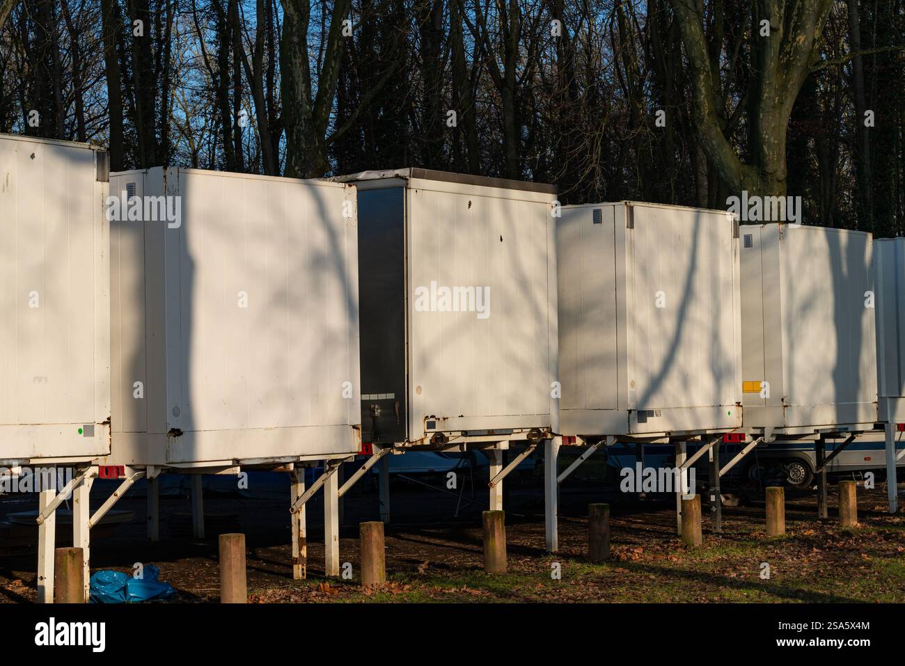 Several white storage car containers are neatly arranged in a wooded ...