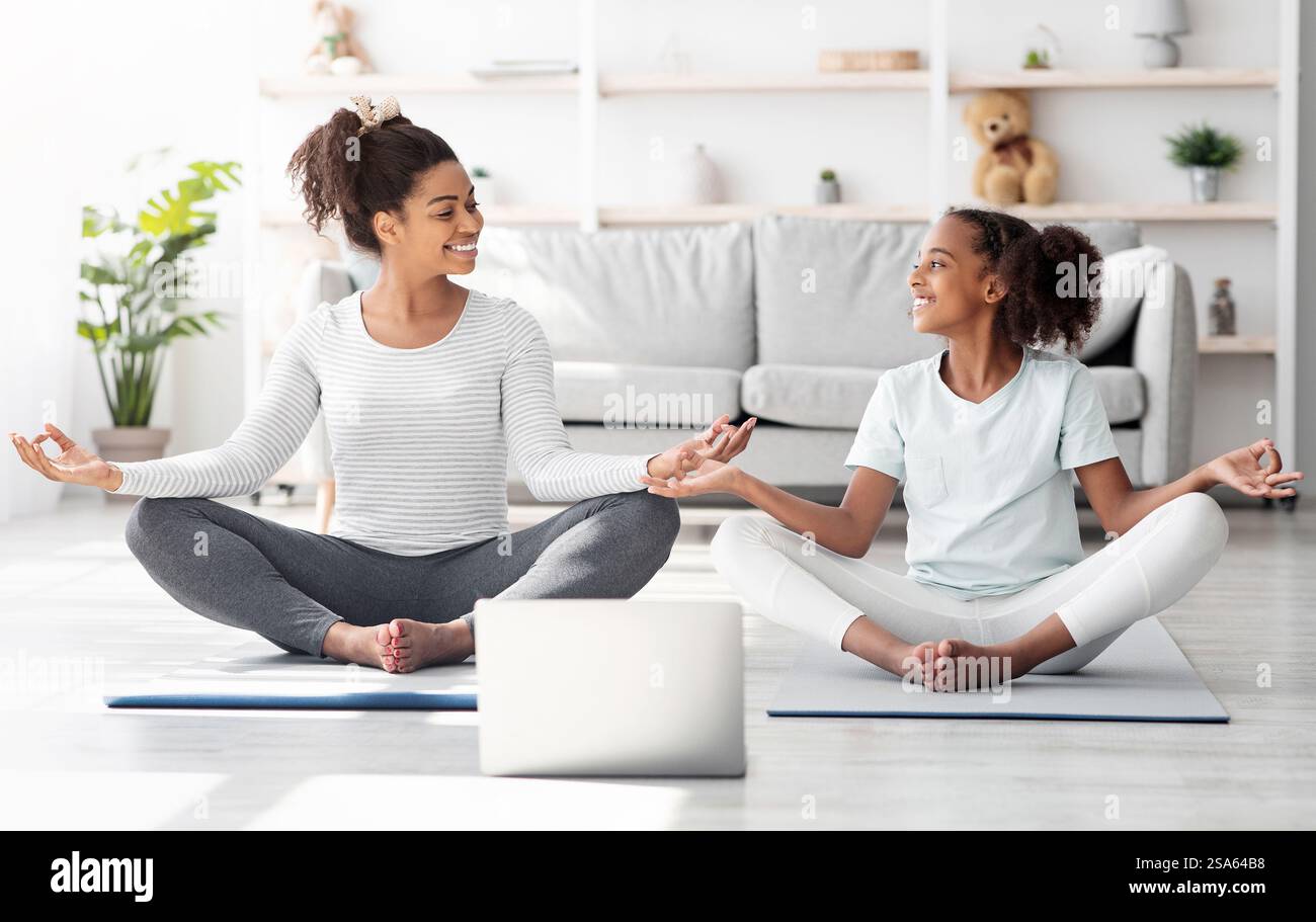 Athletic black mom and daughter having online yoga class Stock Photo ...