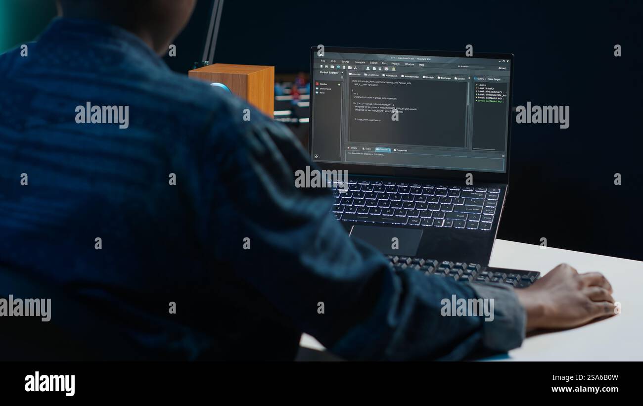 Software developer writes code on laptop screen while in apartment office using Java programming languages. Programmer remotely working on fixing database errors while working from home, camera A Stock Photo