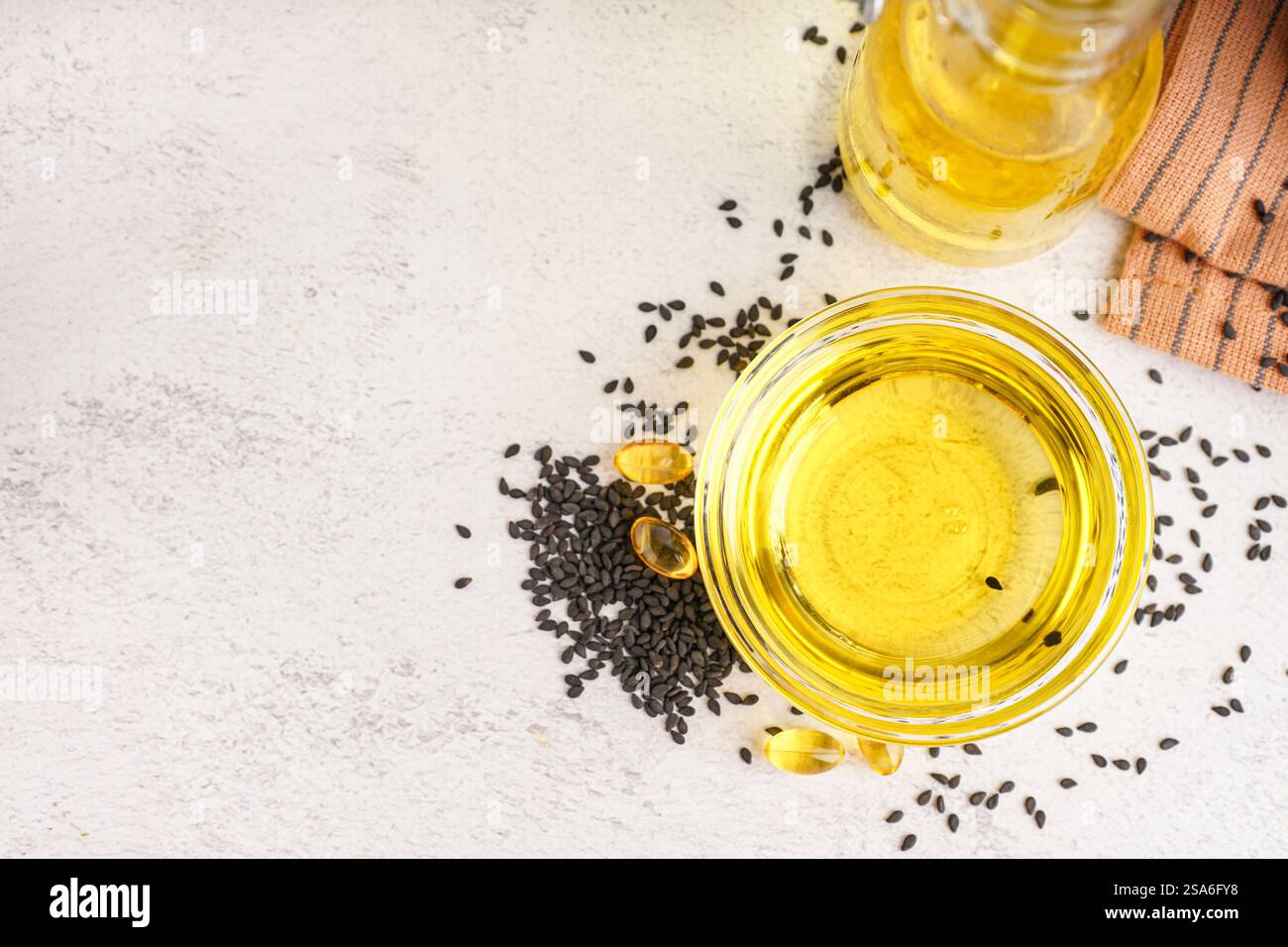 Bowl of oil with sesame seeds and capsules on white background Stock ...