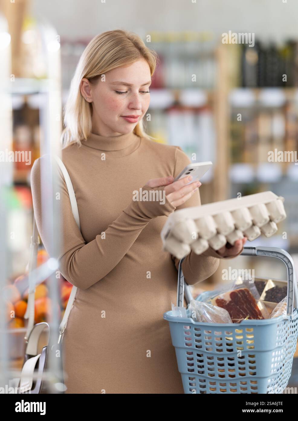 Girl scan QR code, take reading eggs label using phone camera in shop ...