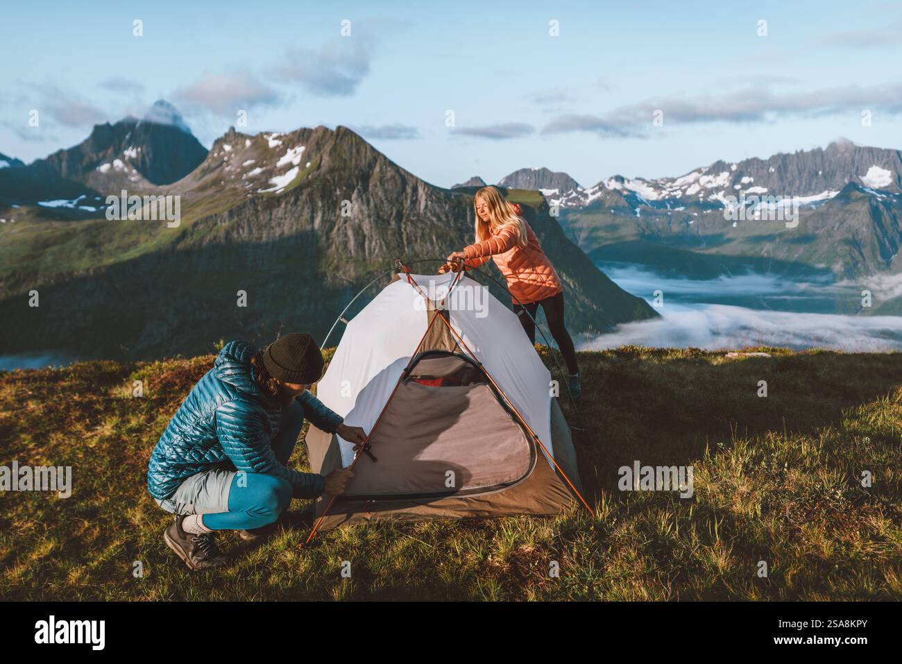 Couple friends preparing their camping tent gear in Norway mountains, active vacations man and woman hiking together adventures outdoor family time he Stock Photo