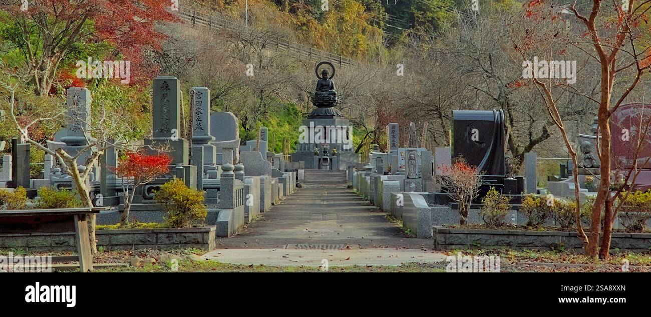 Daytime view of the cemetery at Tokuunin, a Buddhist temple in western Tokyo, with colorful autumn foliage visible all around Stock Photo