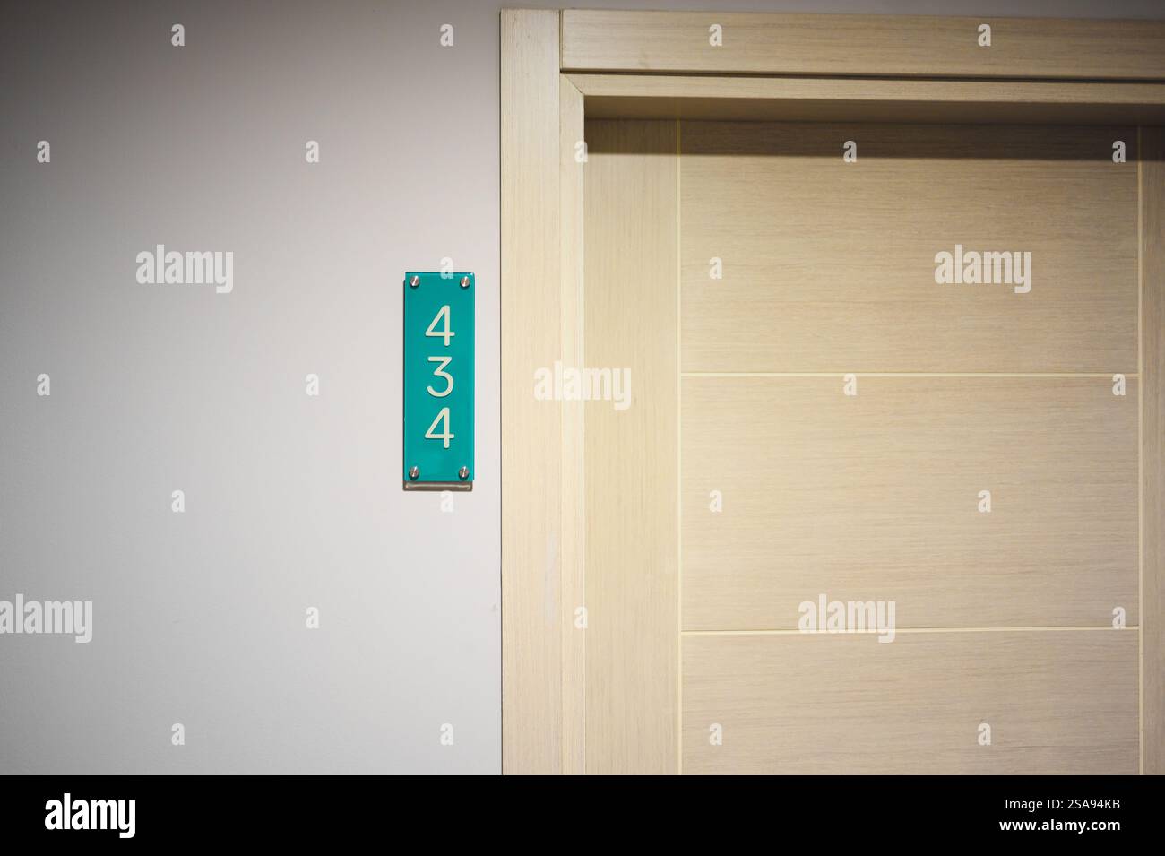 Sign with number on wall of hotel, next to entrance door. Number 434 ...