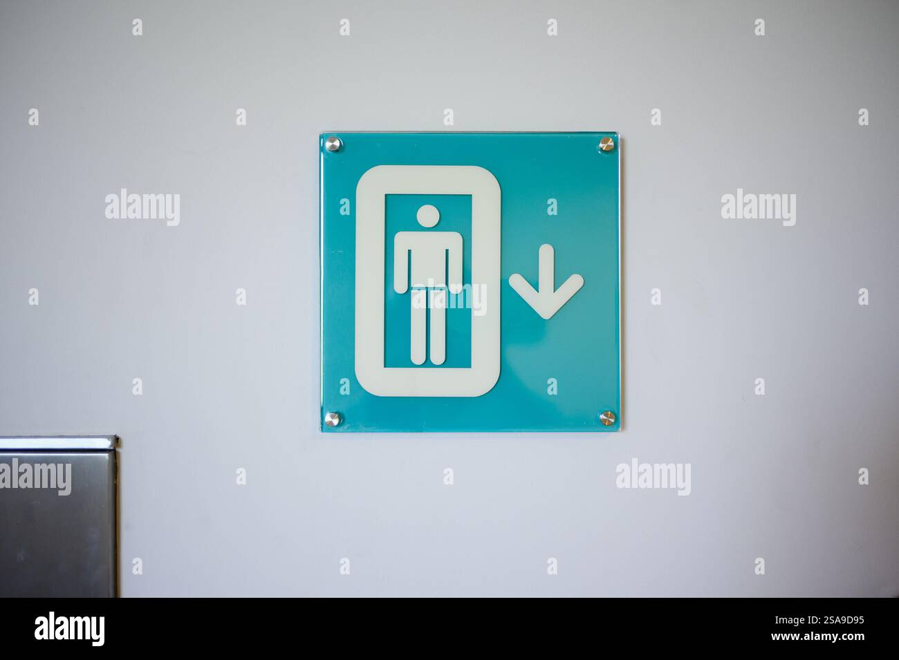 Sign depicting person in elevator with downward arrow. Signpost in office, shopping center, hotel.Descent indicator in case of emergency Stock Photo
