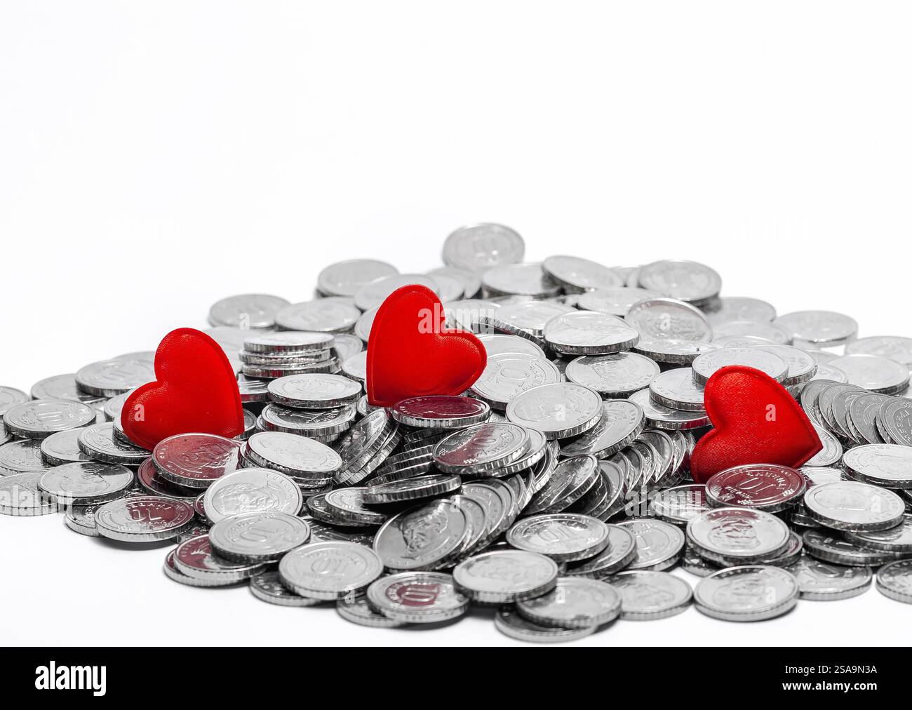 Scattered silver coins and several red hearts isolated on white. Idea for design. Valentine's Day card Stock Photo