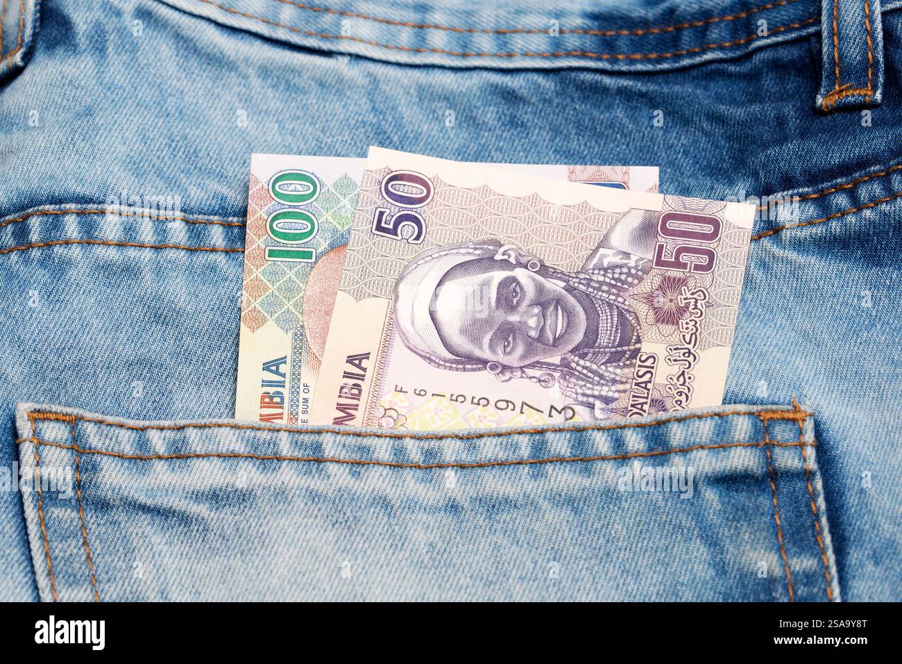 Old Gambian money - dalasi in the pocket of blue jeans Stock Photo
