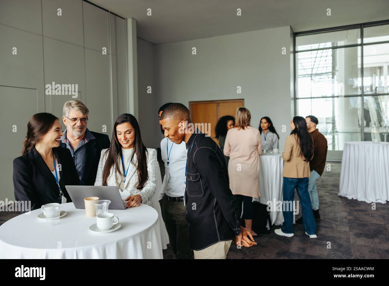 Diverse group of business professionals collaborating and networking in a conference environment, focused on teamwork and idea exchange. Emphasizing c Stock Photo