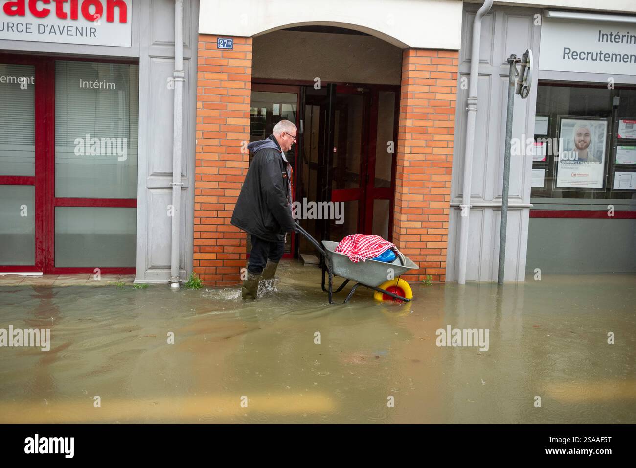 A man uses a wheelbarrow in a flooded street as severe flooding hits ...