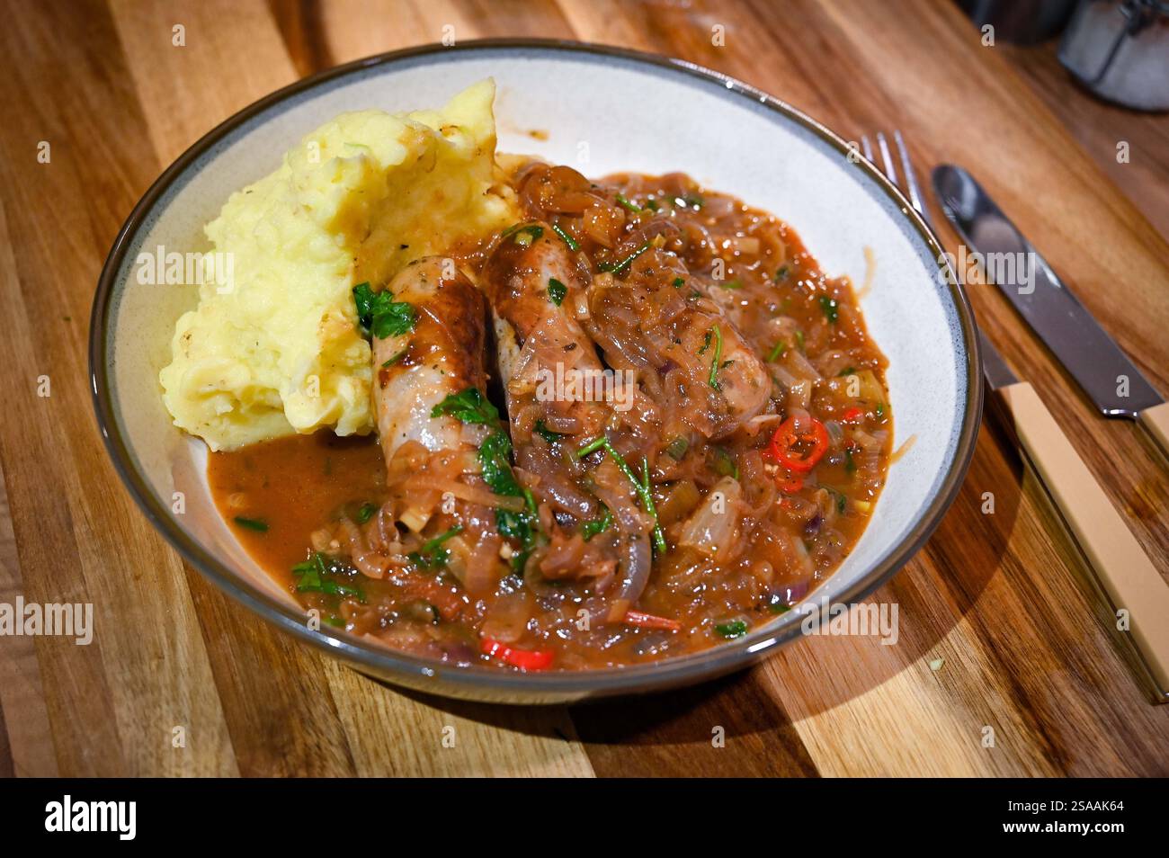 Home cooking making sausage and potato with leeks mash with an onion and chilly gravy casserole : Credit Simon Dack Stock Photo