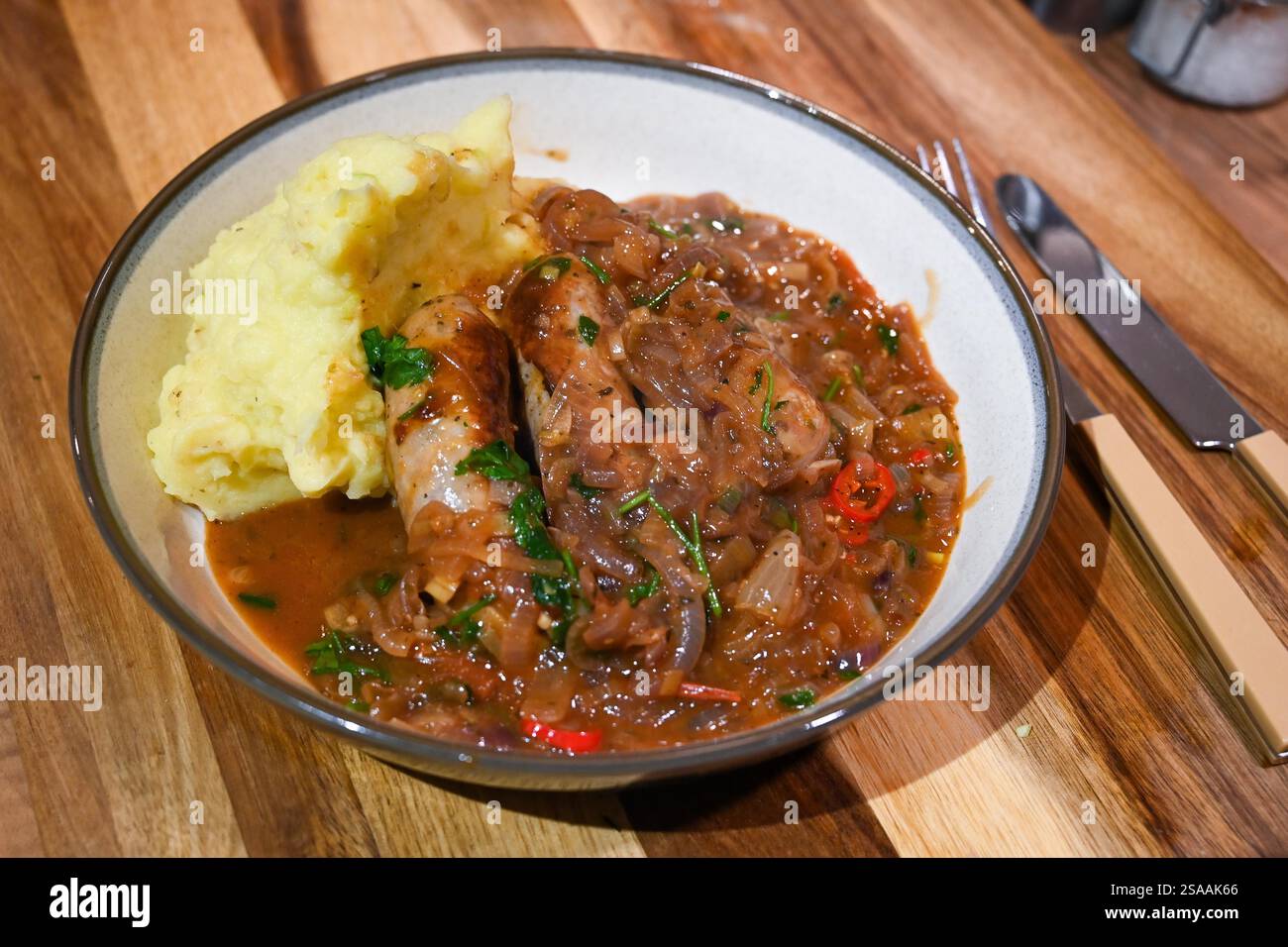 Home cooking making sausage and potato with leeks mash with an onion and chilly gravy casserole : Credit Simon Dack Stock Photo
