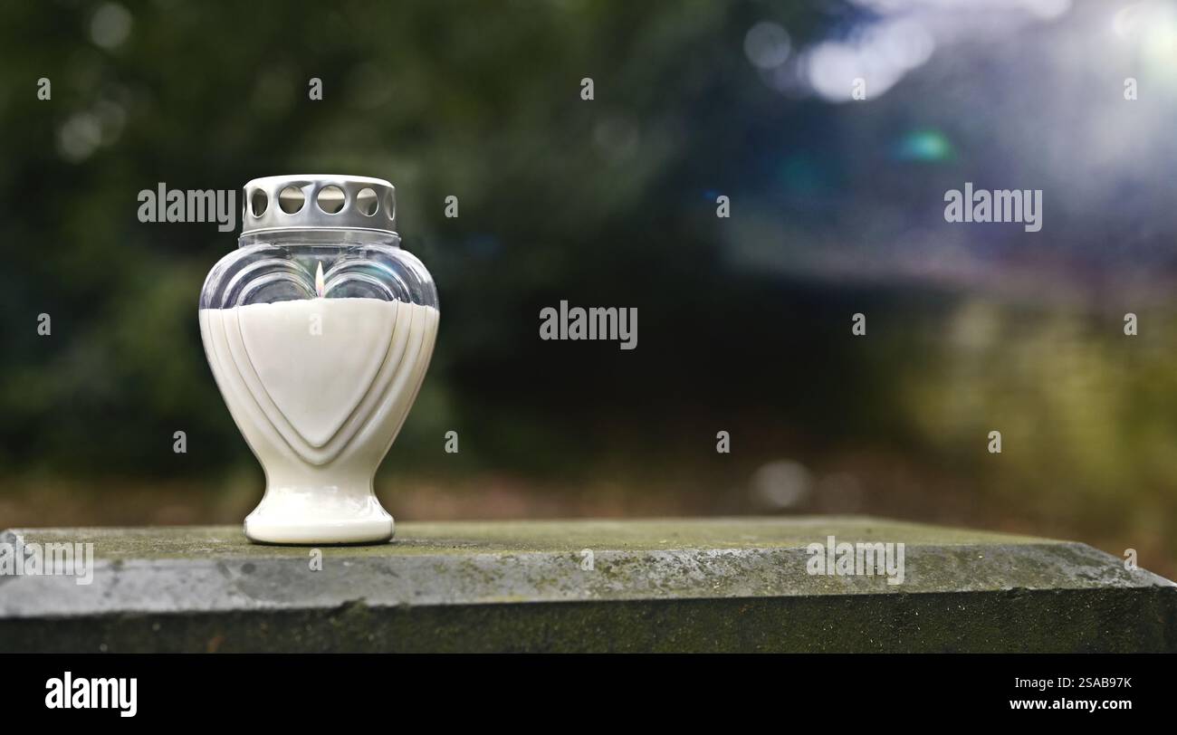 heart-shaped cemetery candle on a grave in the cemetery.. Panoramic image with copy space. Stock Photo