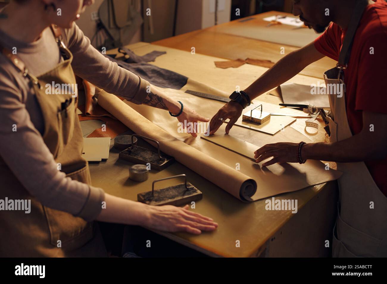 Two artisans working together at a well-equipped workbench, measuring ...