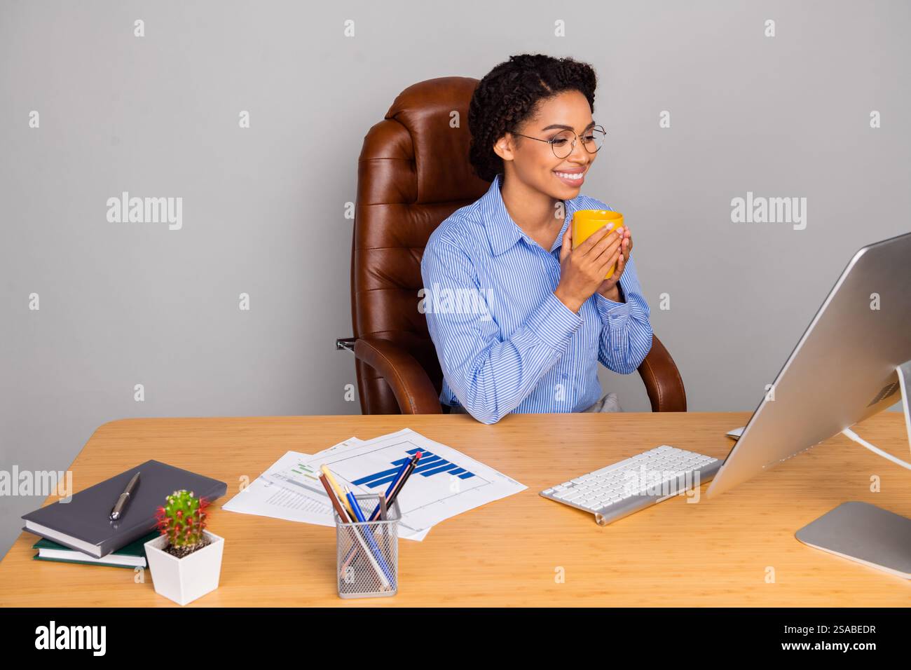 Confident businesswoman enjoying a coffee break while working at her ...
