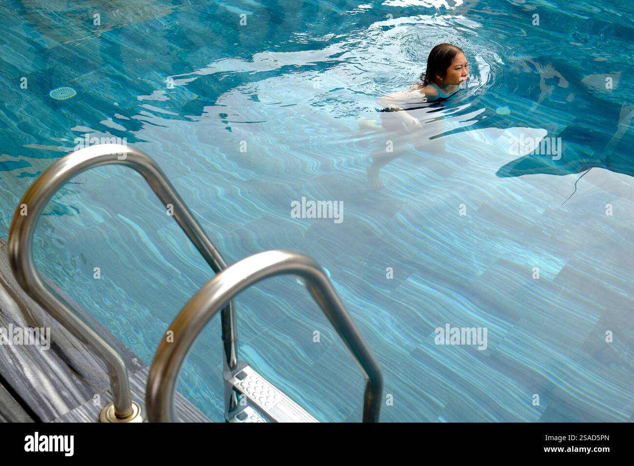Swimming pool in a luxury hotel. Woman on vacation enjoying the water ...