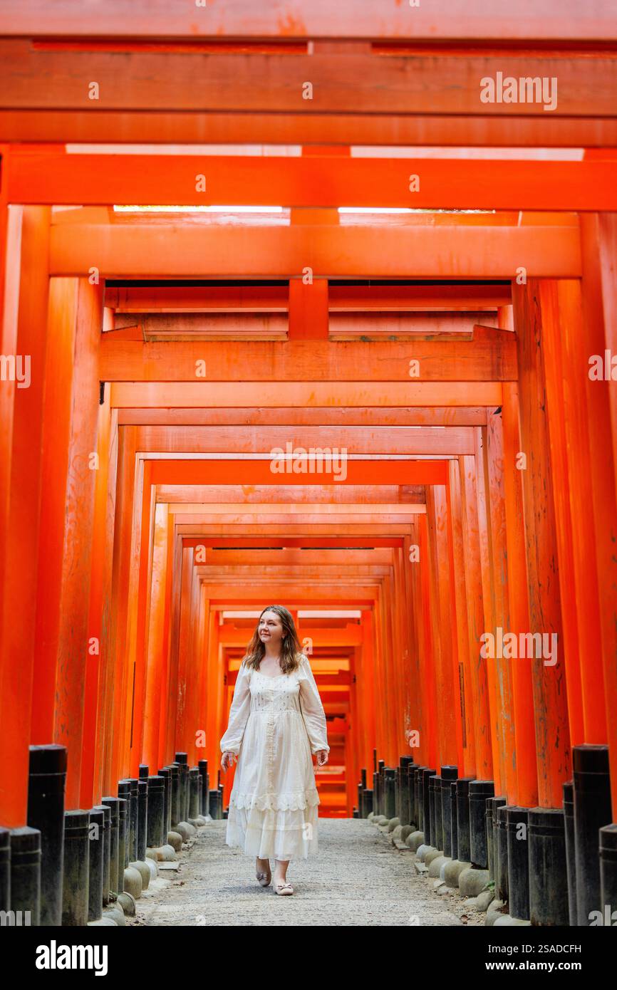 Beautiful woman walking through Red Torii gates in Fushimi Inari shrine ...