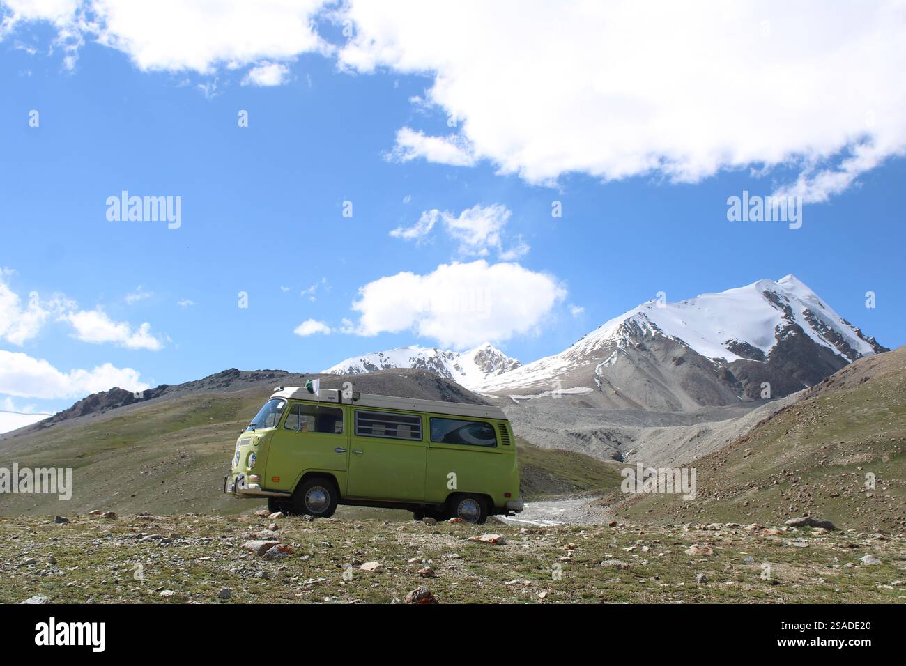 Green vintage camper van parked in a remote mountainous landscape with ...