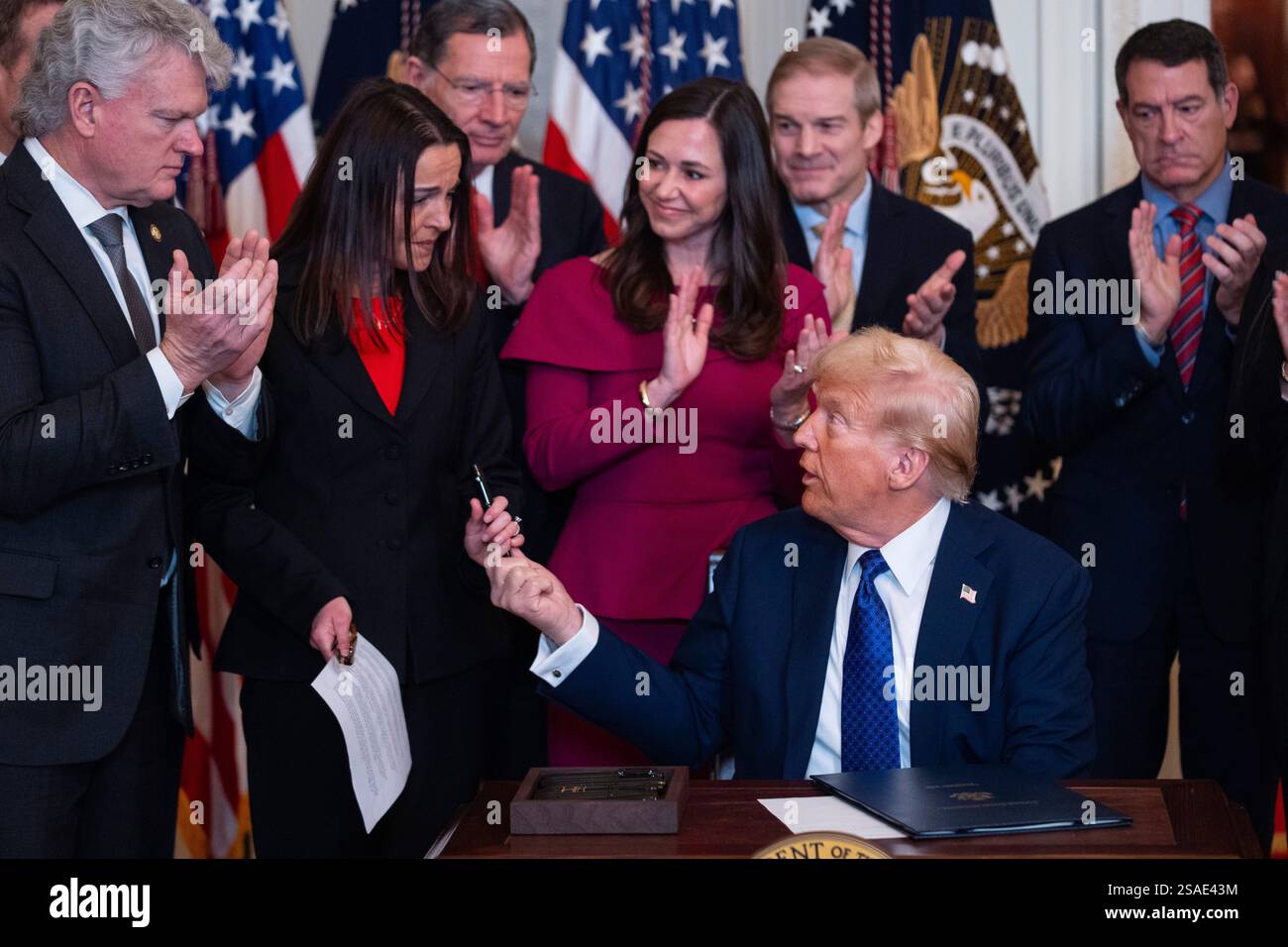President Donald Trump hands a pen to Allyson Phillips, mother of Laken ...