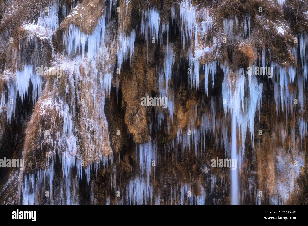 Winter frozen waterfall with icicles on moss-covered rocks Stock Photo ...