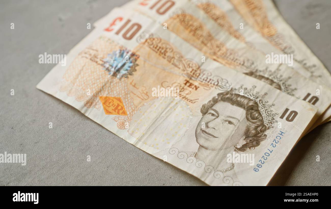 British ten pound banknotes laid out on a grey concrete surface ...